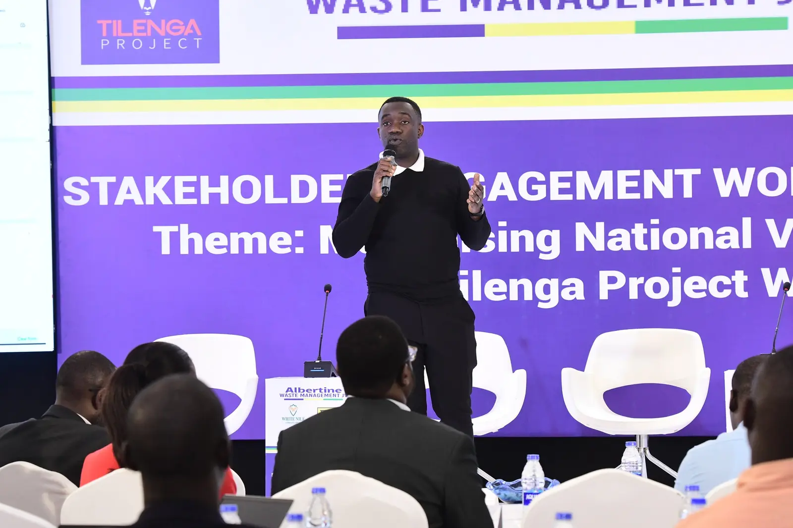 Speaker in front of the Tilenga Project stakeholder engagement banner