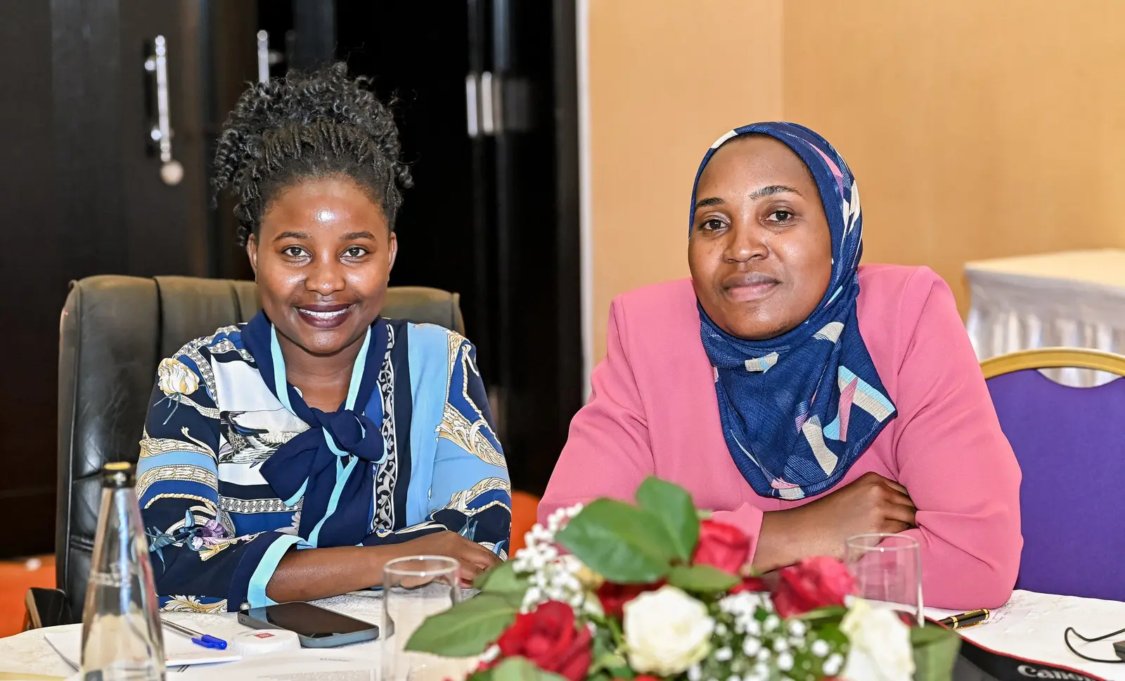 Two delegates smiling at a forum table