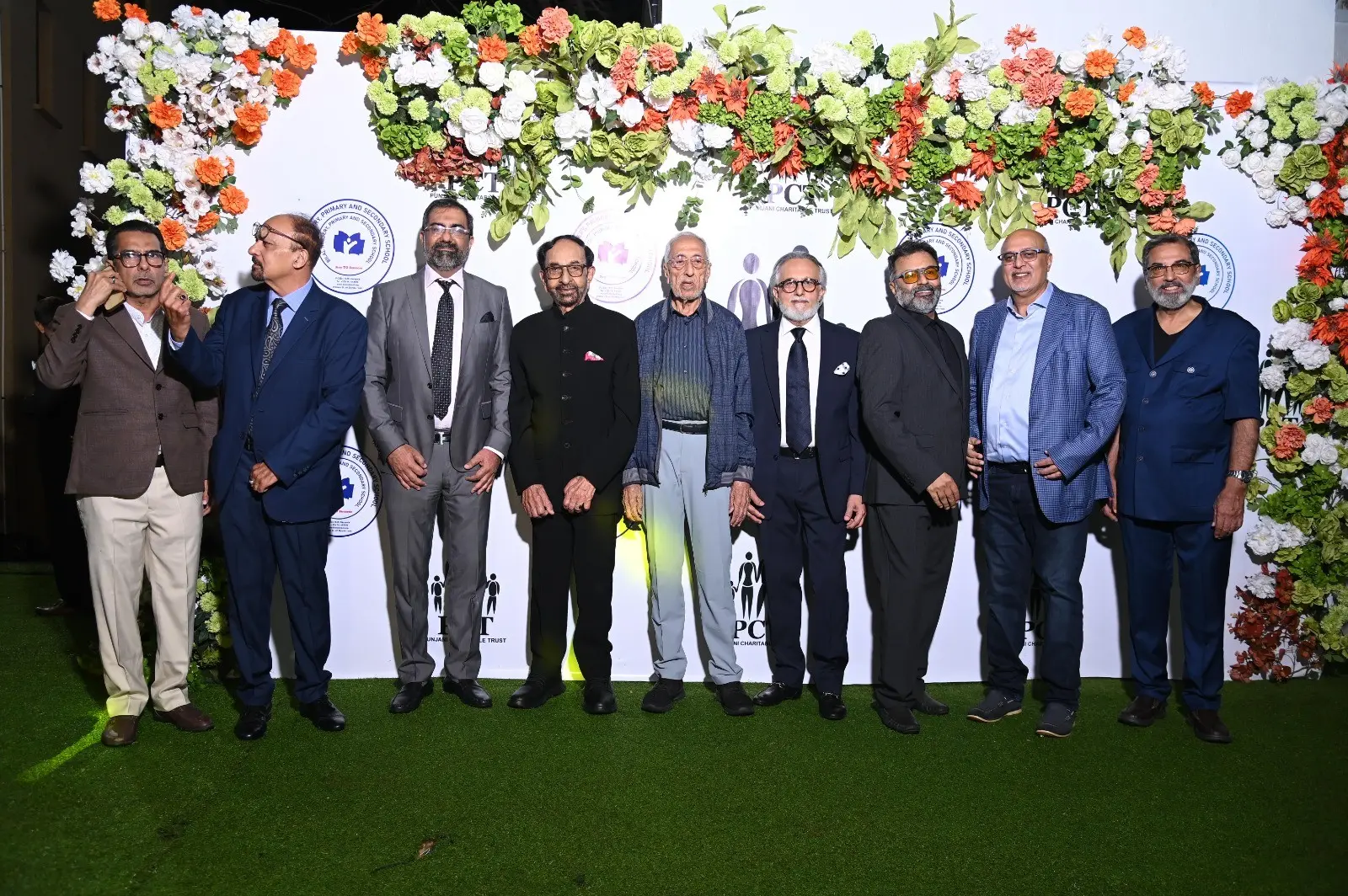 Guests gathered in front of a floral wall at the Punjani Charitable Trust event